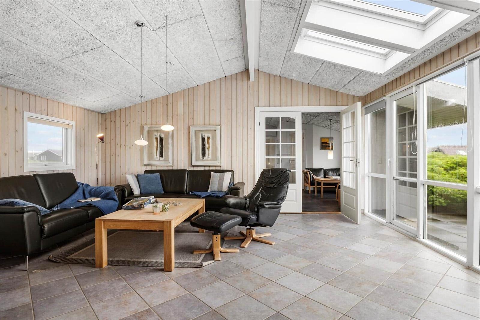 Wohnzimmer mit Ledersofa, Holztisch und Blick auf Garten