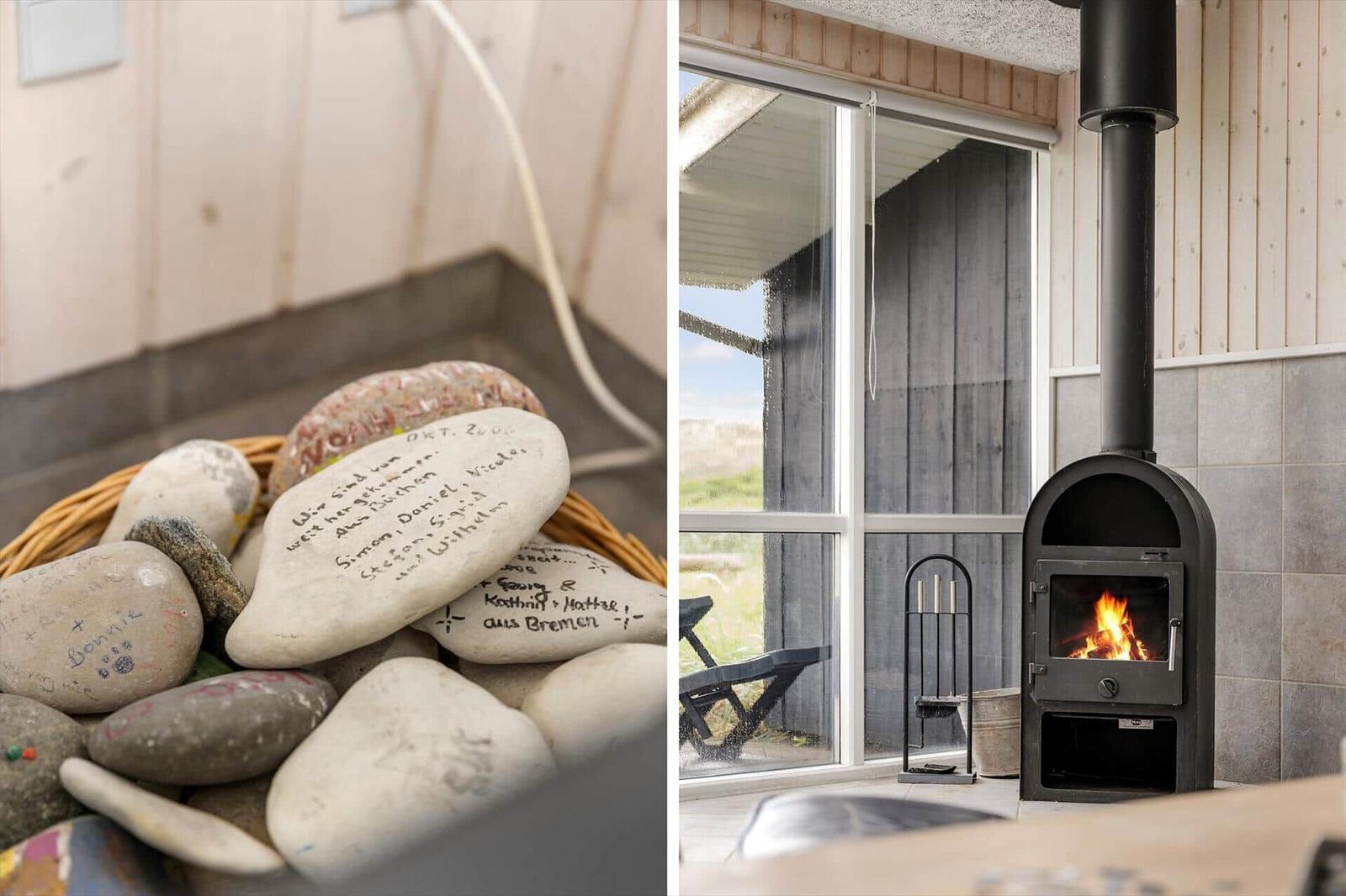 Badezimmer mit Korb voller geschriebener Steine. Holzofen mit brennendem Feuer vor großem Fenster.