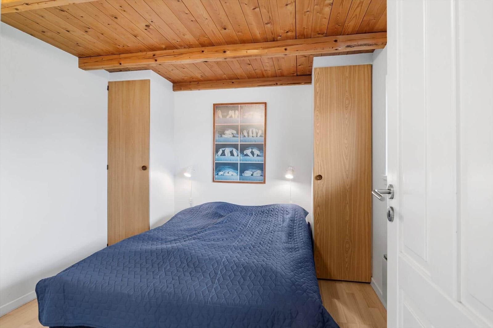 Schlafzimmer mit Bett, Holzdecke und zwei Türen.