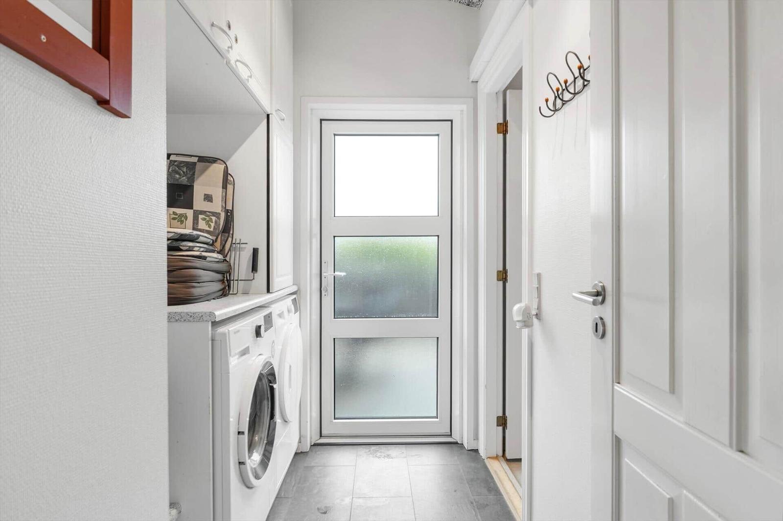 Hinterhof mit Waschmaschine und Garderobe. Tür mit getöntem Glas.