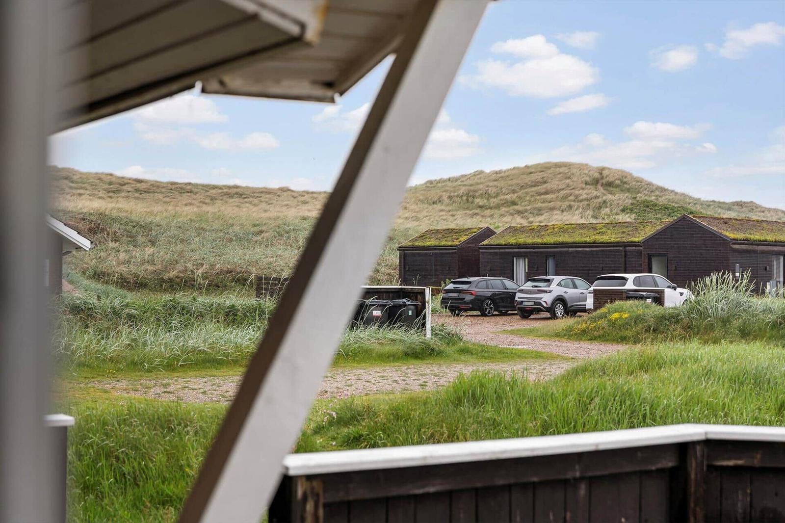 Von der Veranda aus ist eine grüne Landschaft mit Dämmen und geparkten Autos sichtbar.