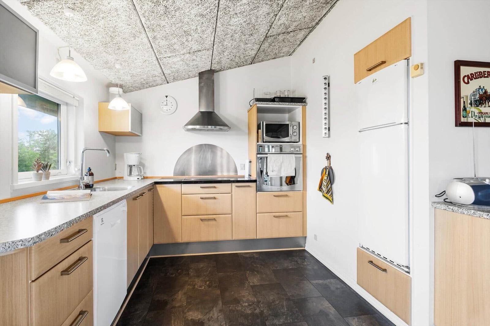 Küche mit Holzschränken, Spüle, Kühlschrank und Backofen.