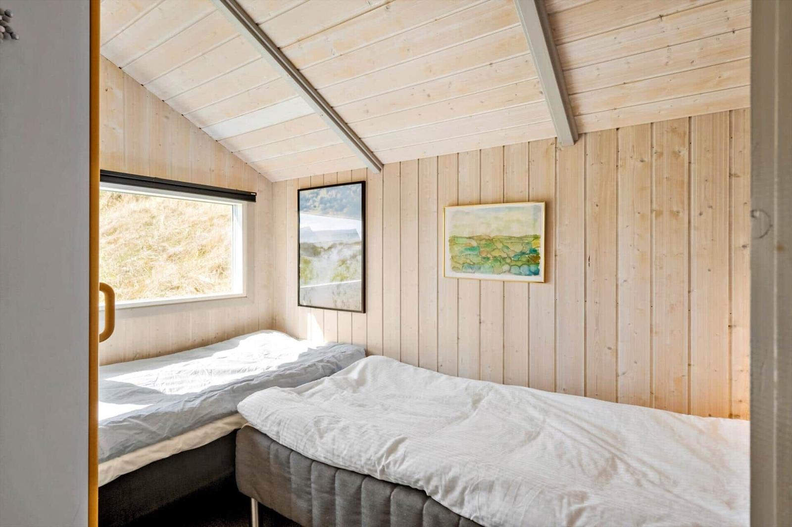 Zwei Betten in einem Holzraum mit Fenster und Wandbildern.