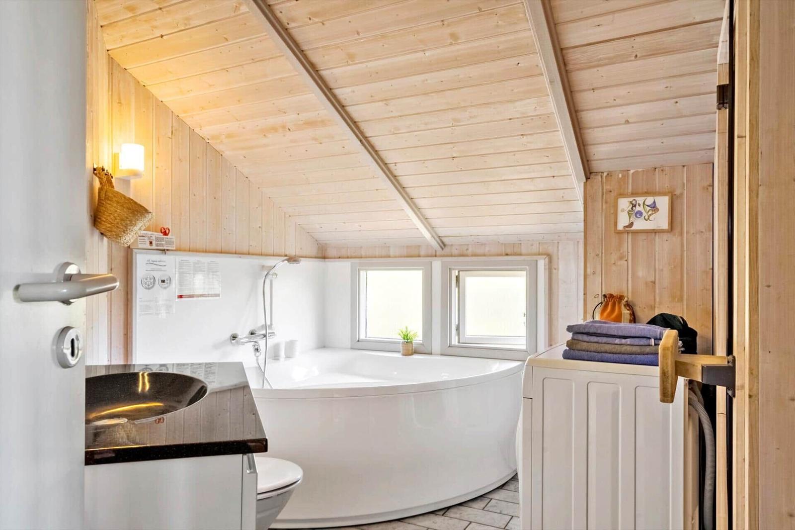 Bad mit Dusche, Badewanne und Fenstern. Holzwände und Decke.