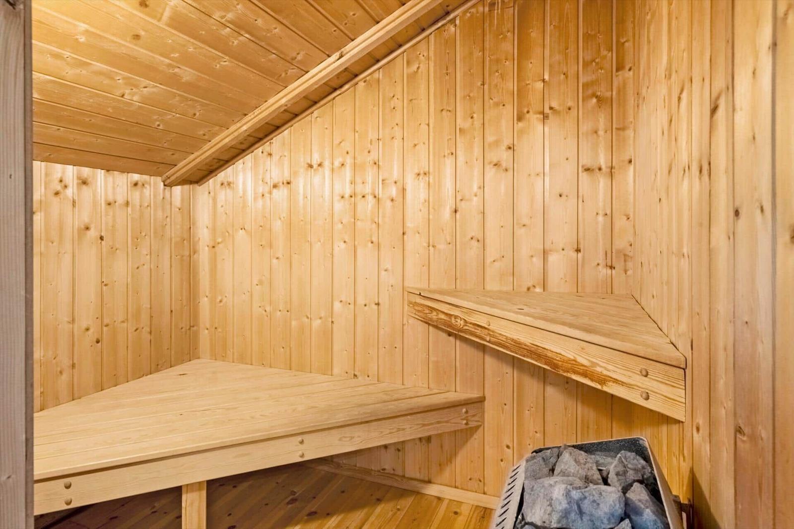 Holzsauna mit Sitzbänken und Steinmulde.