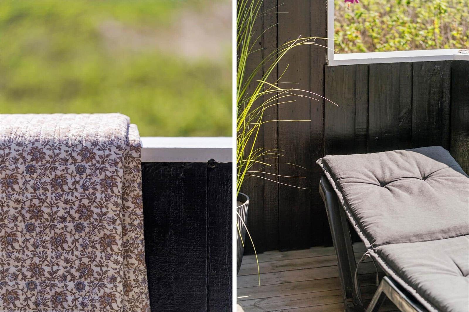 Terrasse mit Sitzmöbeln und Pflanze vor dunklem Holz
