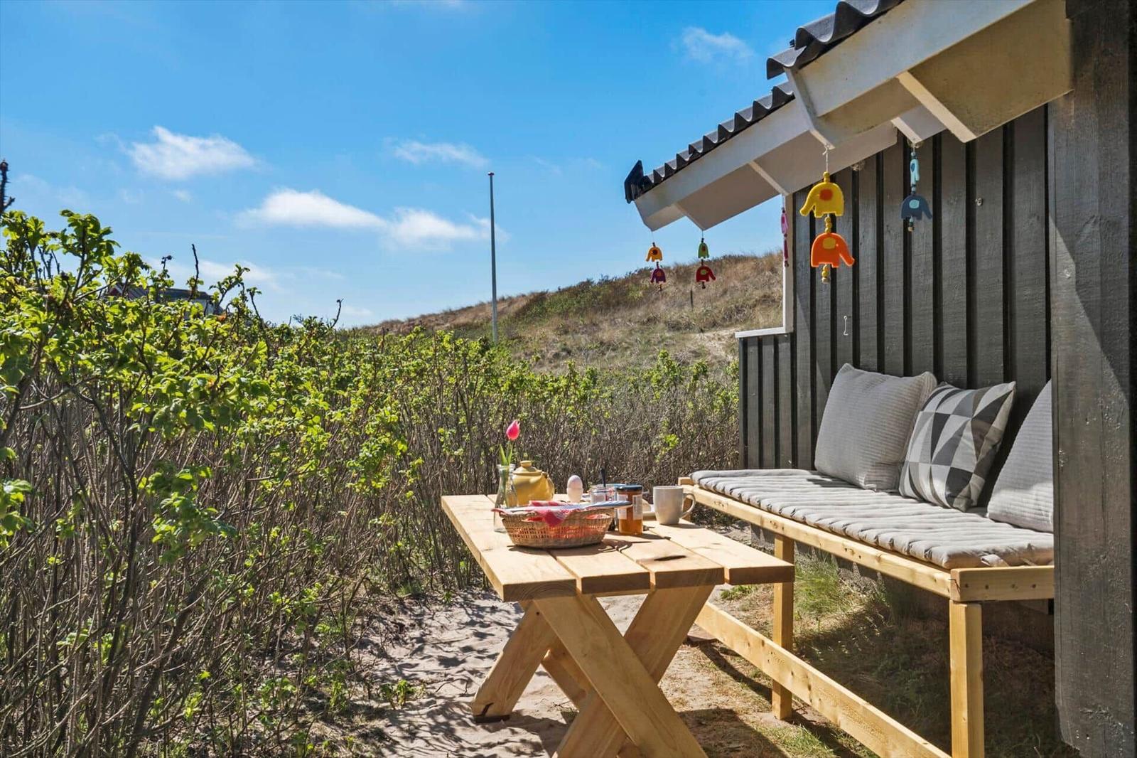 Terrasse mit Holztisch, Bank und Blick auf Hügel