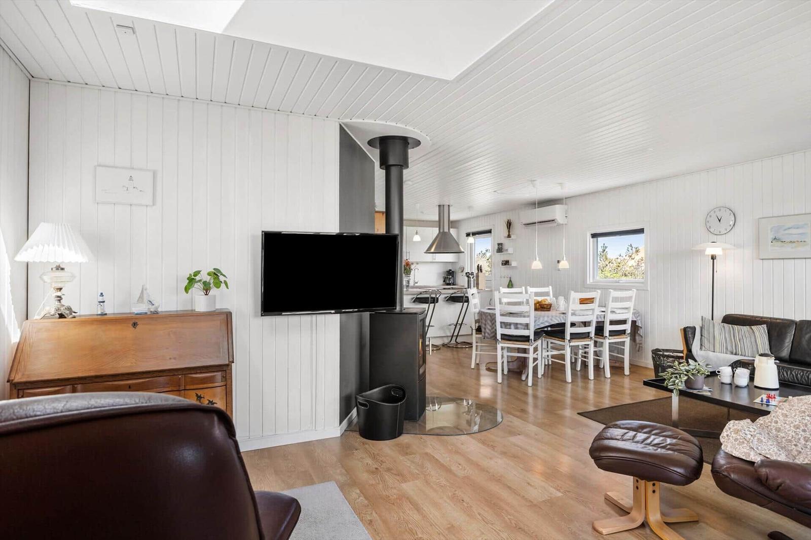 Wohn- und Essbereich mit Holzboden, TV, Kamin und Essplatz mit Tisch und Stühlen.