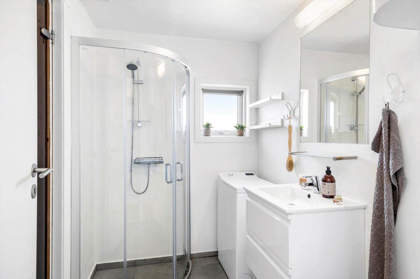Badezimmer mit Duschkabine, Waschmaschine und Spiegelschrank.