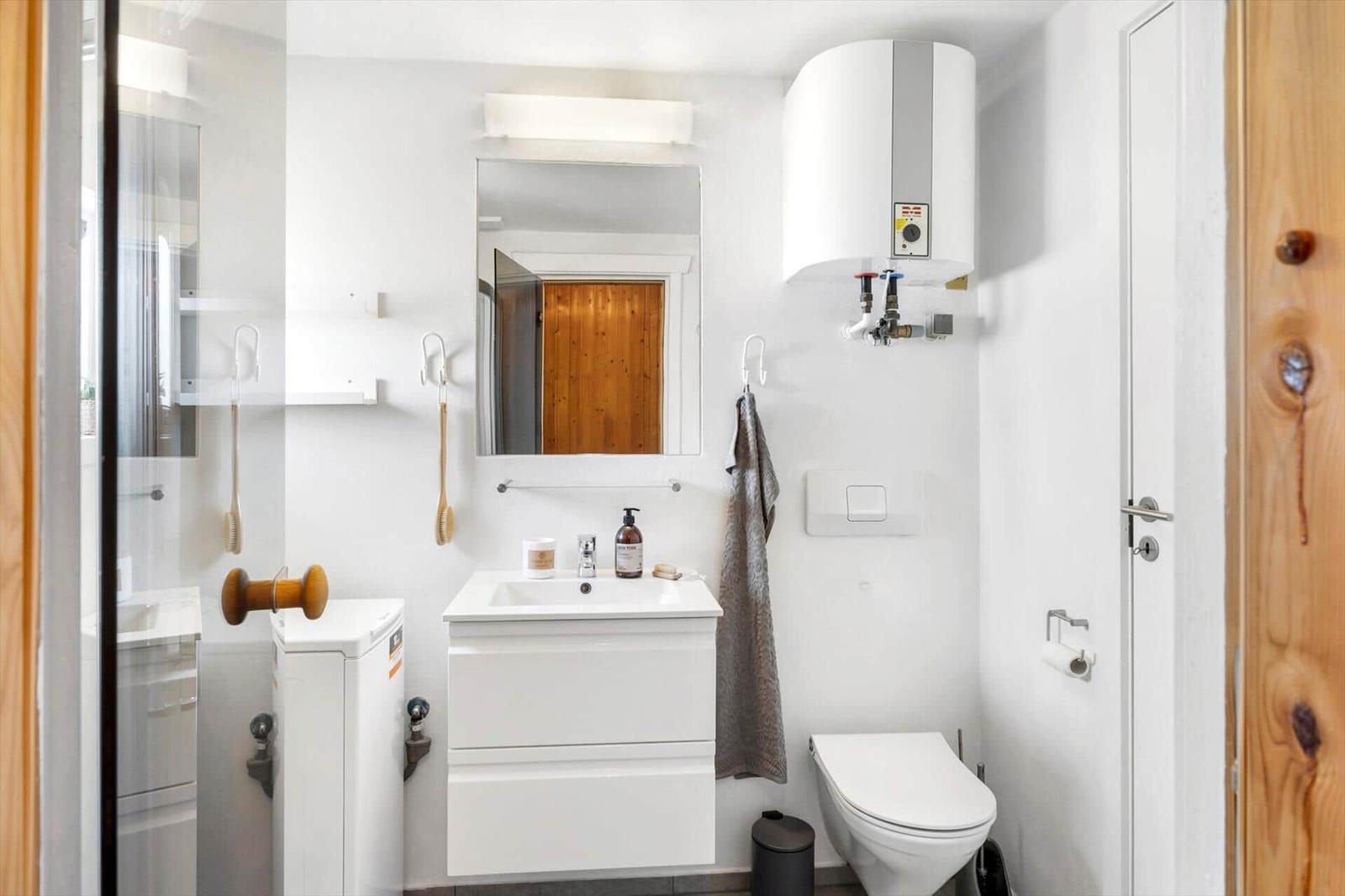 Badezimmer mit Waschbecken, Spiegel, Toilette und Dusche.