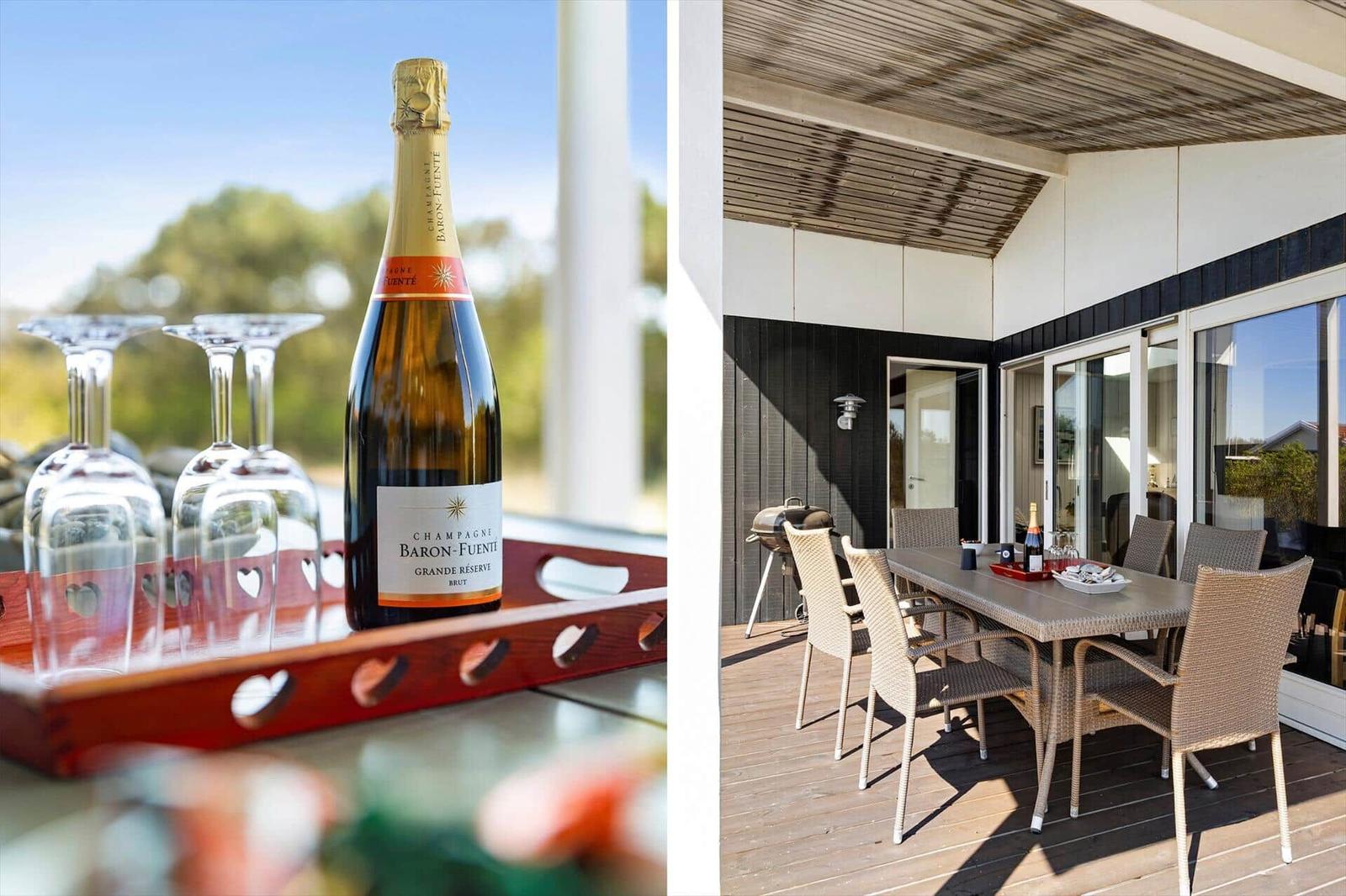 Champagnerflasche und Gläser auf einem Tablett. Terrasse mit Tisch, Stühlen und Grill.
