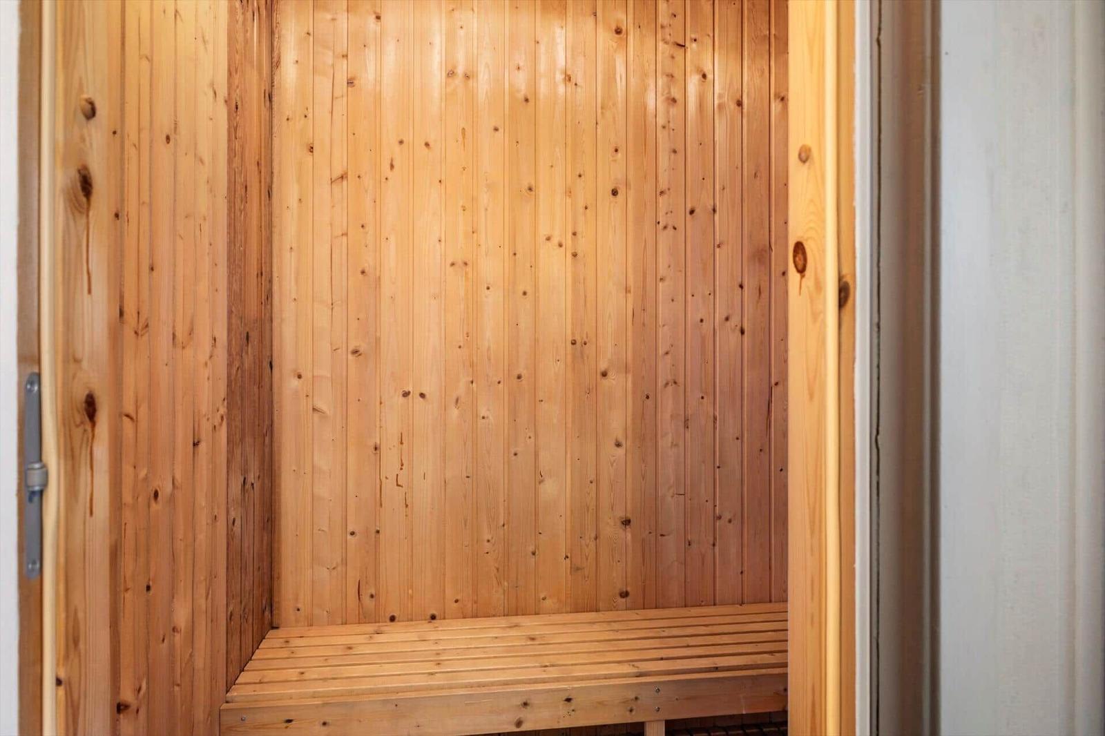 Holzsauna mit Bank und vertikalen Wandpaneelen.