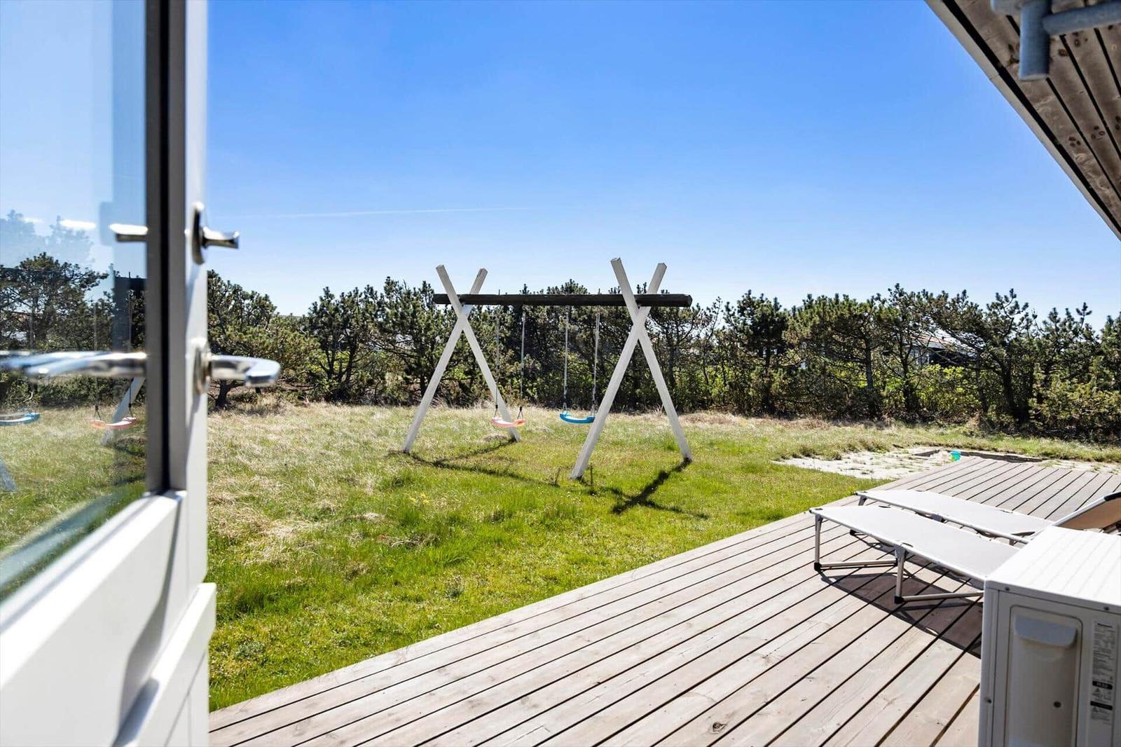 Terrasse mit Liegen und Schaukel im Grünen