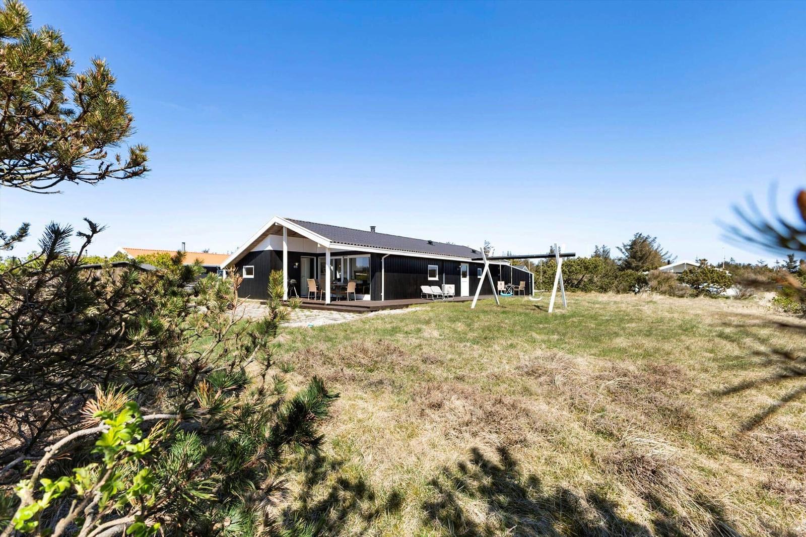 Ein modernes Haus mit Terrasse und Garten unter blauem Himmel.