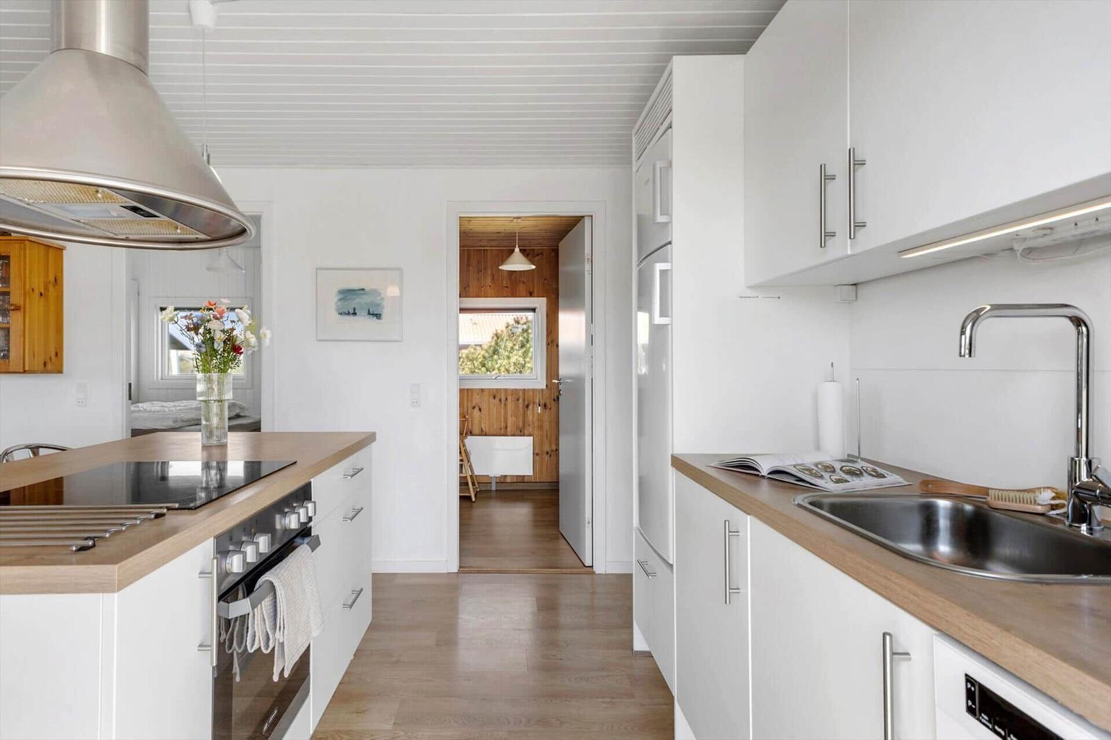 Küche mit Holz Arbeitsplatte, weißen Schränken und Edelstahlspüle.