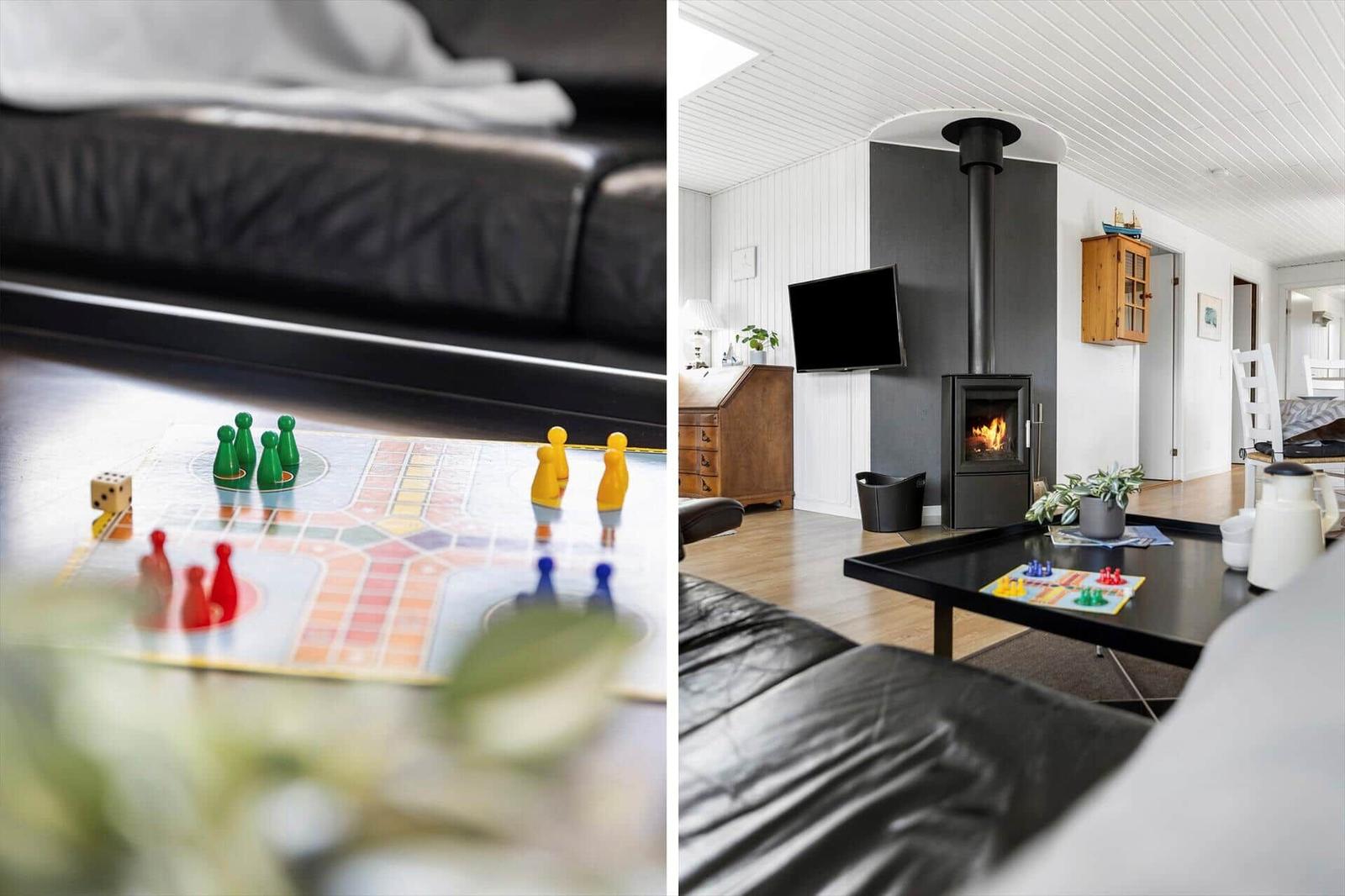 Wohnzimmer mit Kamin, Sofa und Spielplatte. Fernseher und Holzmöbel sind sichtbar.