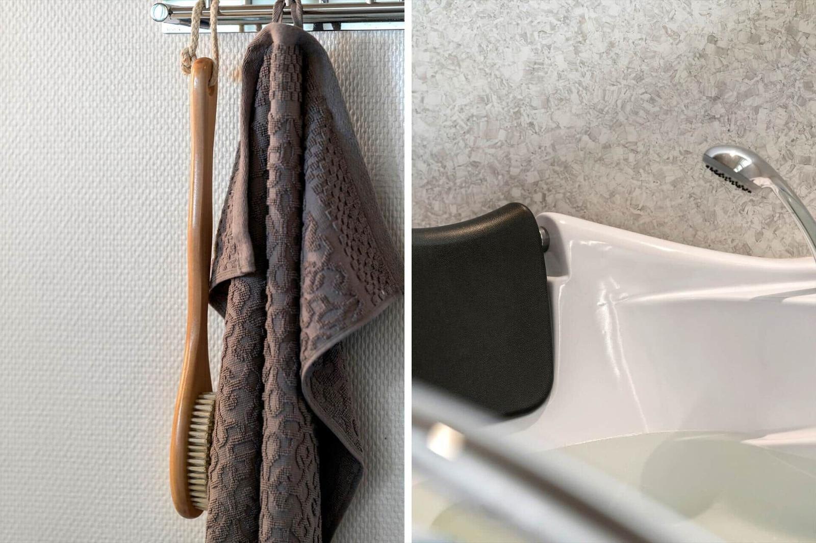 Badezimmer mit Dusche und Handtuchhalter. Braunfarbenes Handtuch und Bürste hängen an einem Haken.