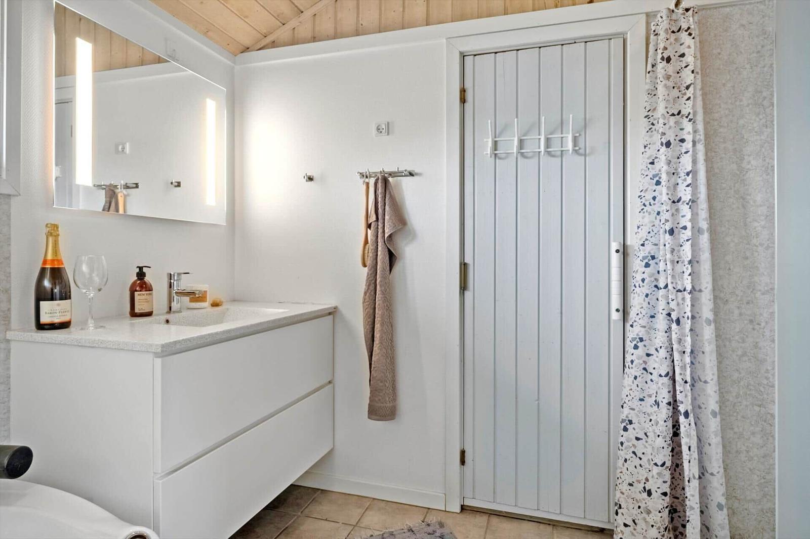 Badezimmer mit Waschbecken, Spiegel, Dusche und Handtuchhalter.