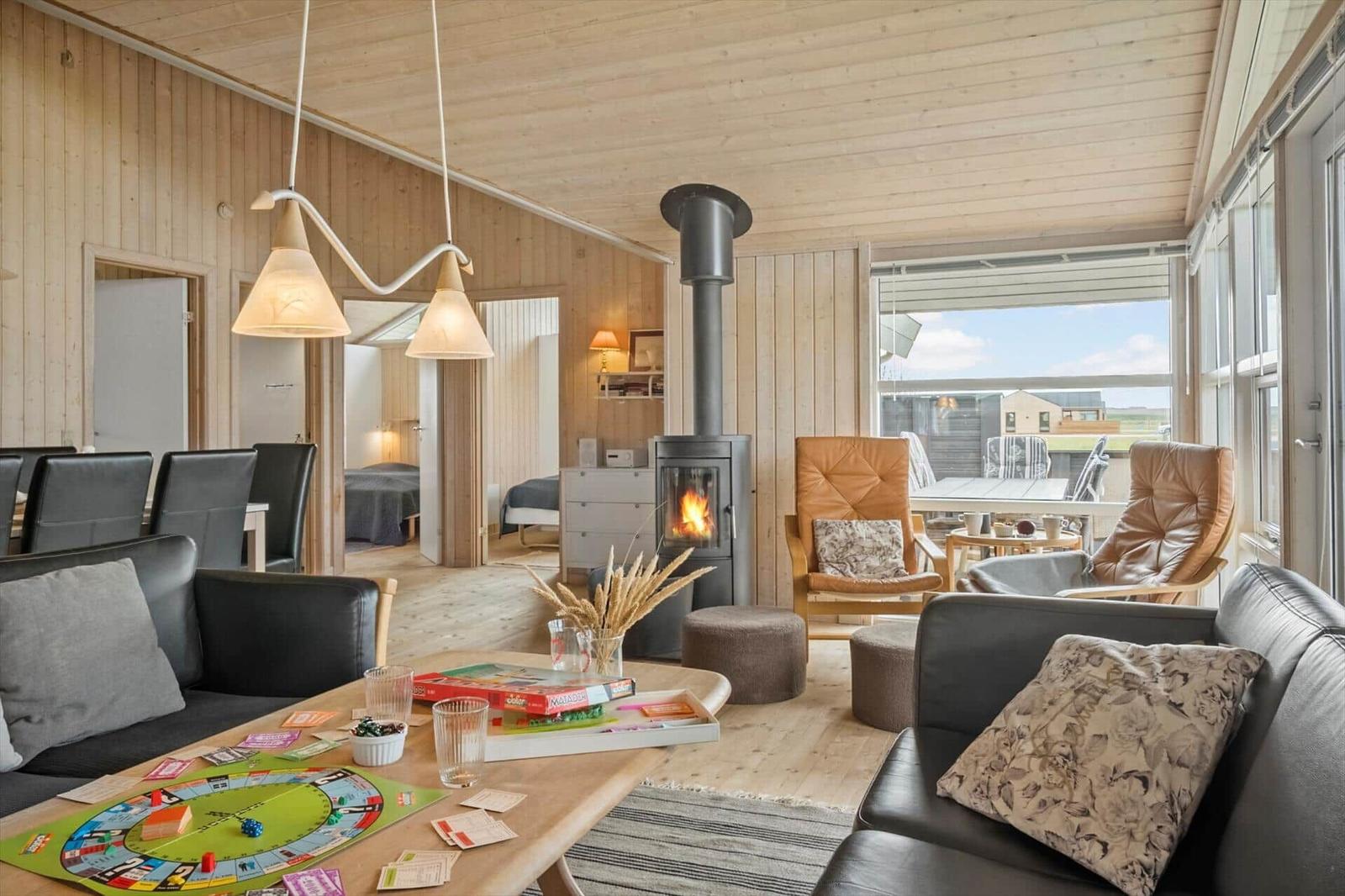 Wohnbereich mit Kamin, Sofa und Sessel. Durchgang zu Schlafzimmer. Blick auf Terrasse.