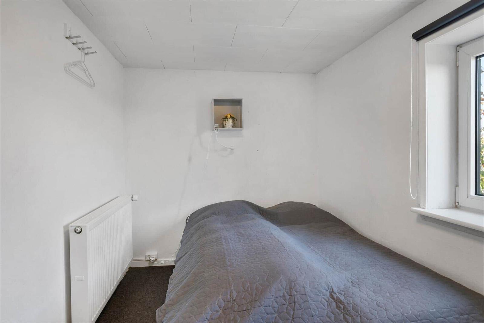 Schlafzimmer mit Bett, Fenster und Heizkörper an der Wand.