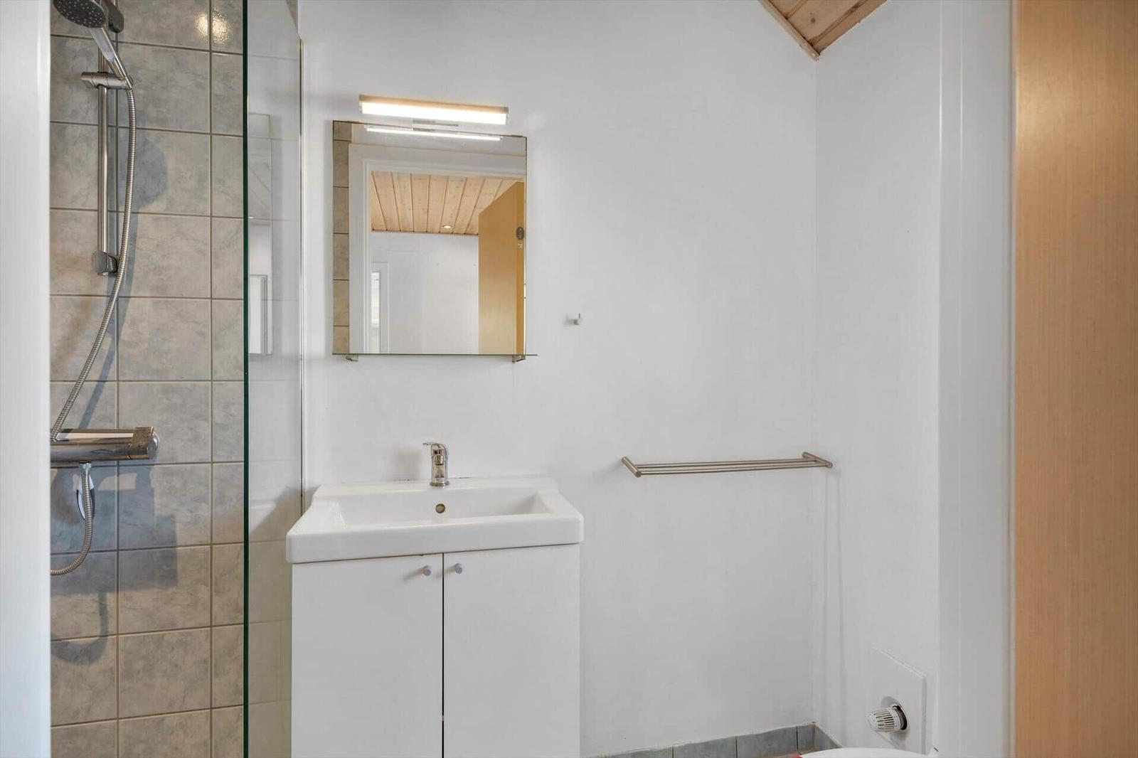 Badezimmer mit Dusche, Waschbecken und Spiegel.