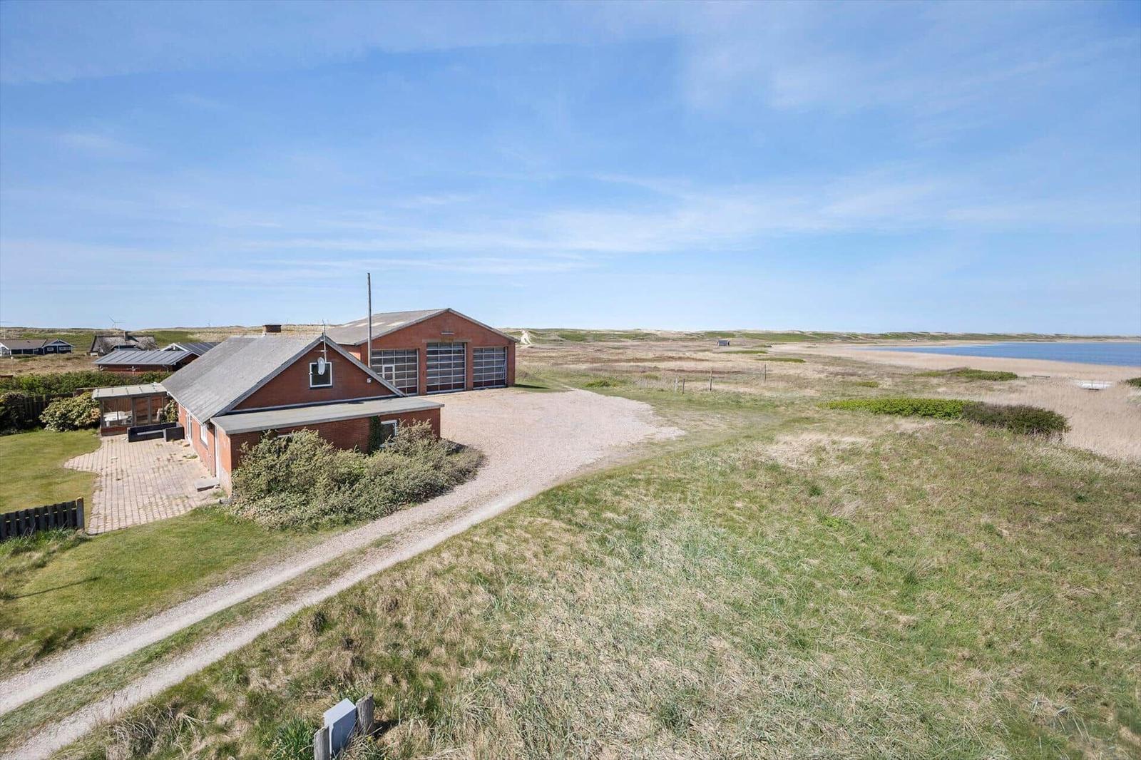 Rotes Haus mit Garage auf Grasland neben Strand und Meer.