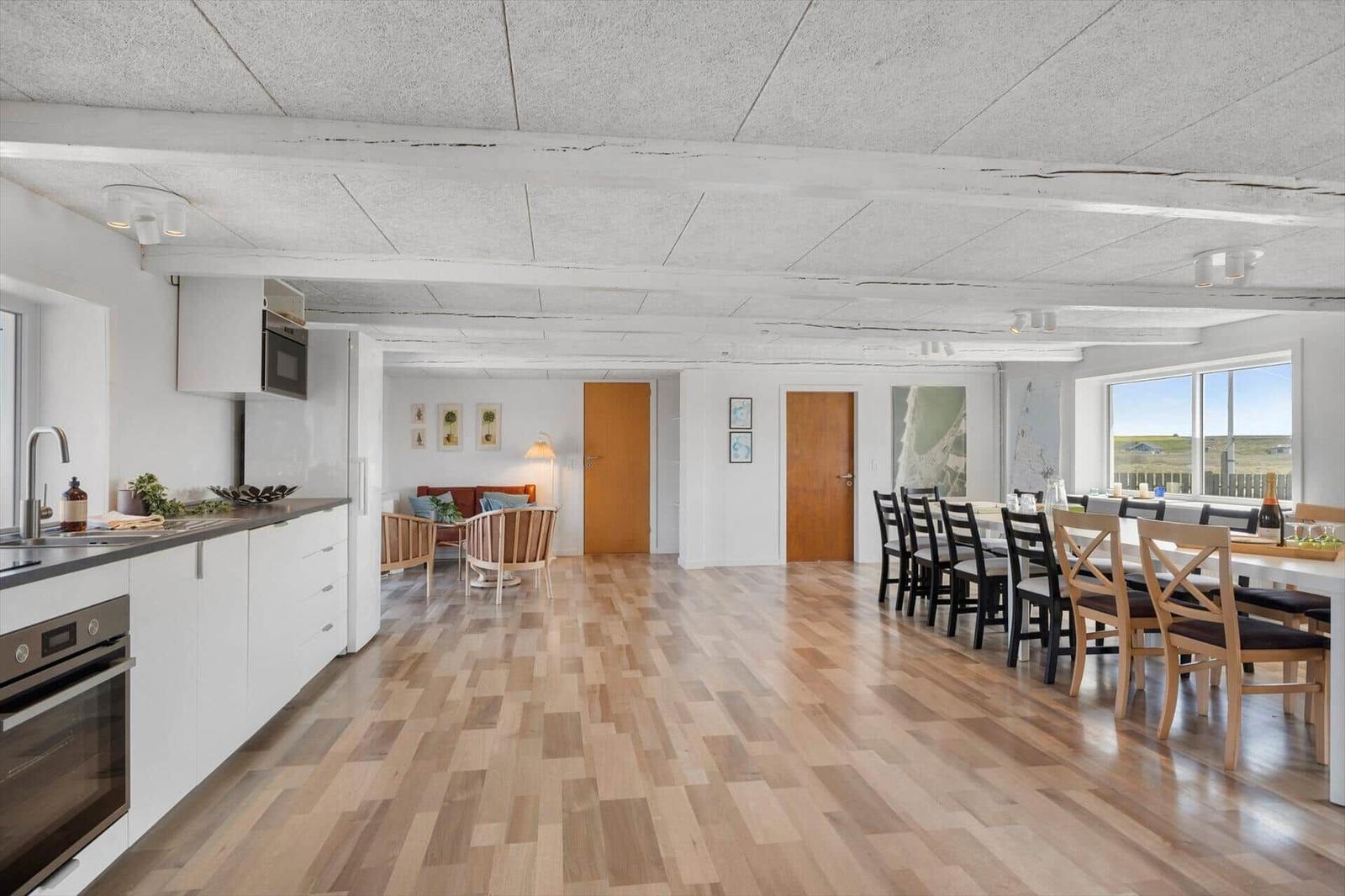 Küche, Essbereich und Wohnzimmer mit Holzboden und weißen Wänden.