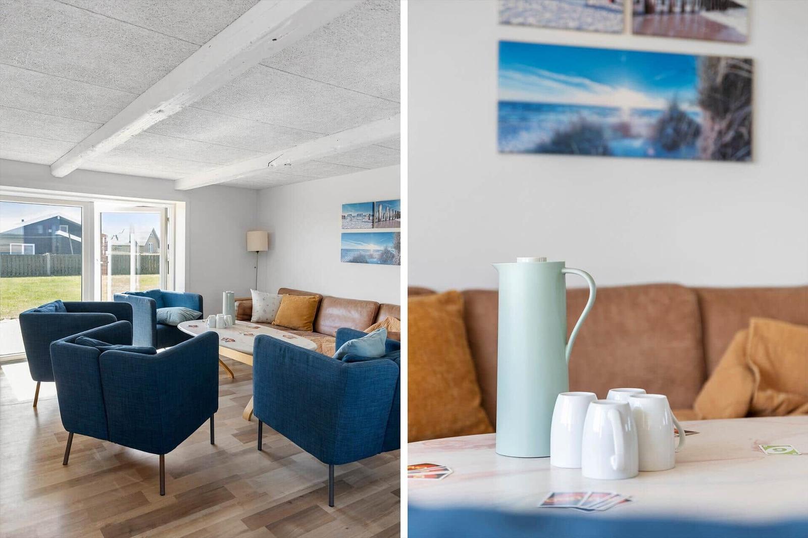 Wohnzimmer mit blauen Sesseln, braunem Sofa und Holzboden. Tisch mit Thermoflasche und Tassen.