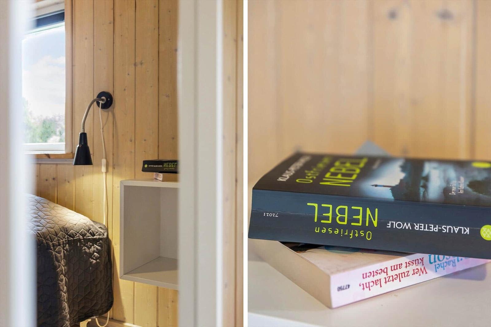 Schlafzimmer mit Holzwand, Bett und Nachttisch. Bücher auf dem Tisch.
