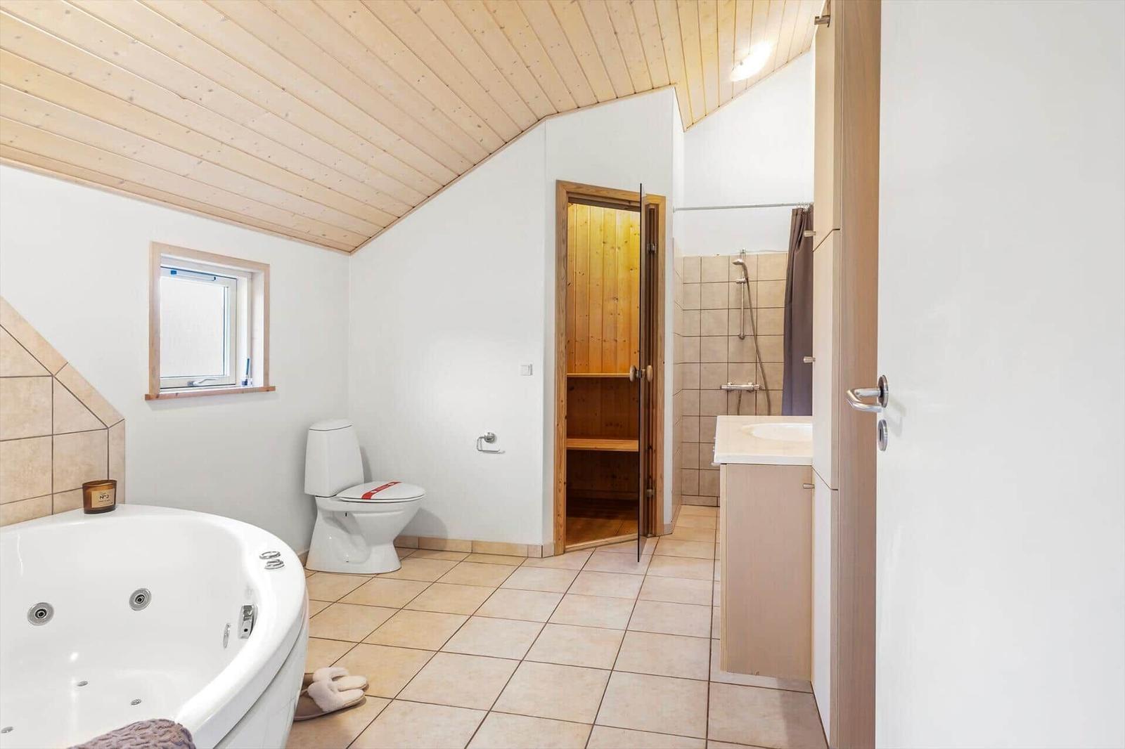 Bad mit Whirlpool, Toilette, Dusche und Sauna.