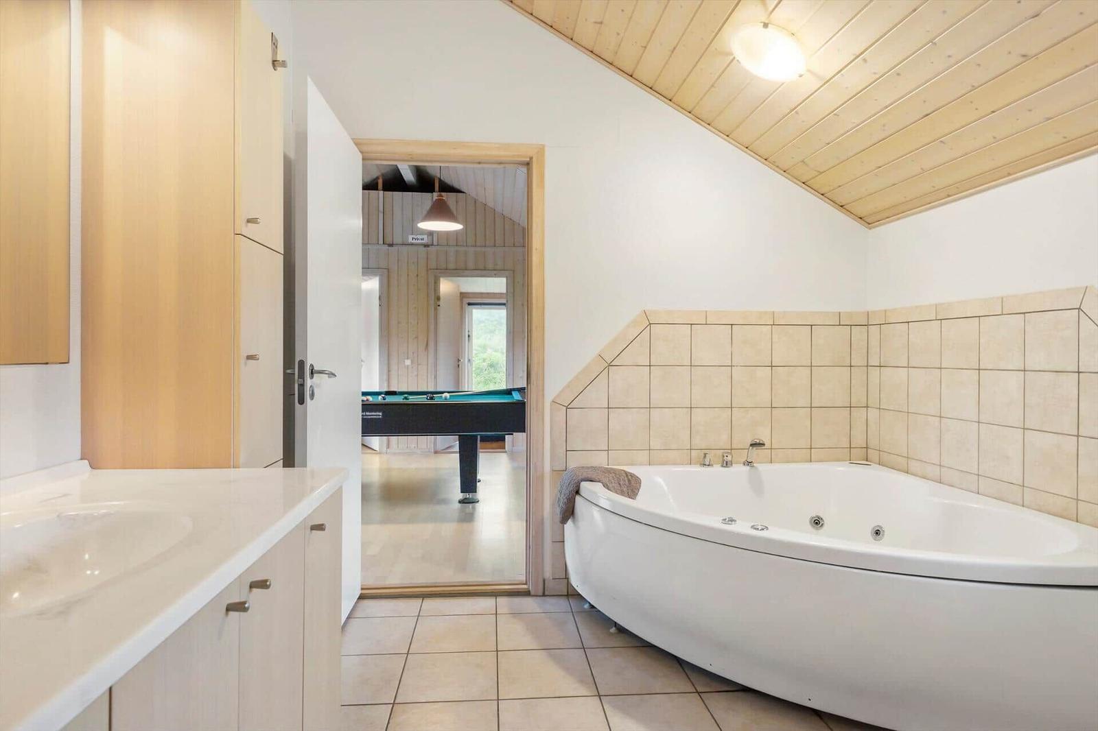 Bad mit Whirlpool und Blick in Spielzimmer mit Billardtisch.