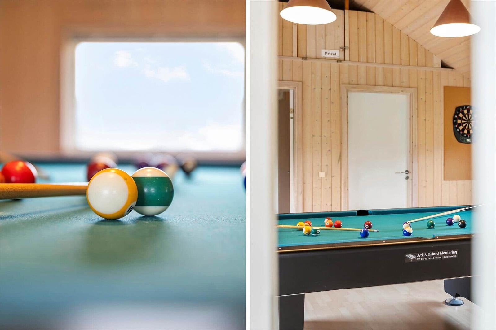 Billardtisch mit Kugeln und Stöcken in einem Holzraum mit Fenster und Tür.