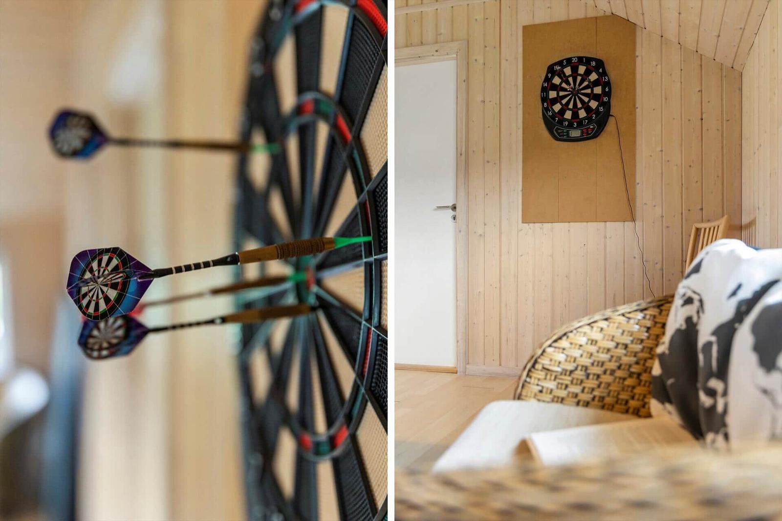 Dartboard an Holzwand mit Stühlen und Tür im Hintergrund