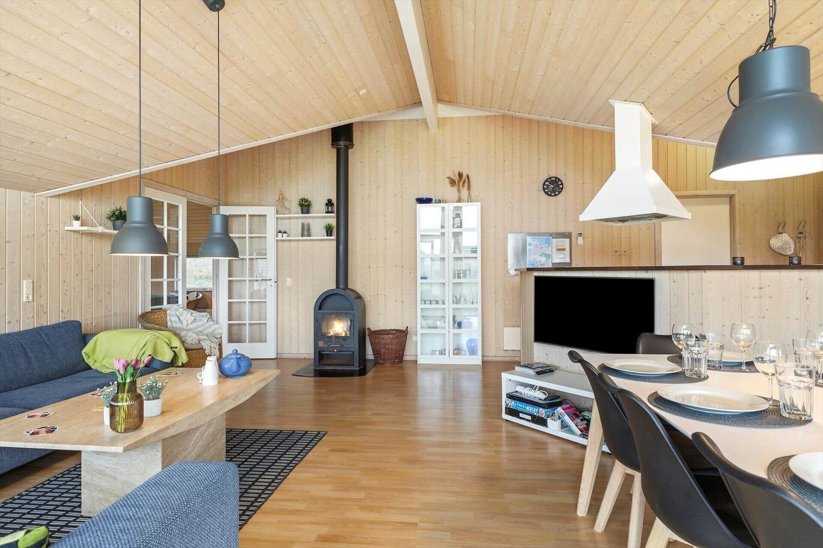 Wohn- und Essbereich mit Holzdecke, Kamin und Esstisch.