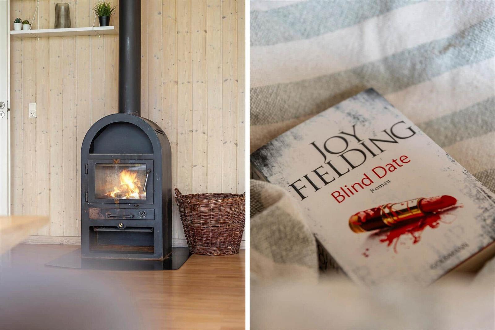 Kaminofen in Holzwand und Buch auf Bett