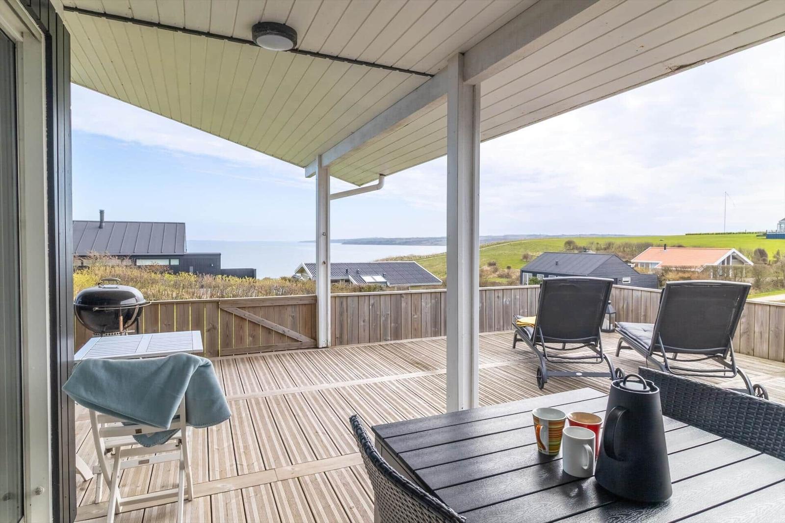 Terrasse mit Grill, Sitzgelegenheiten und Meerblick.