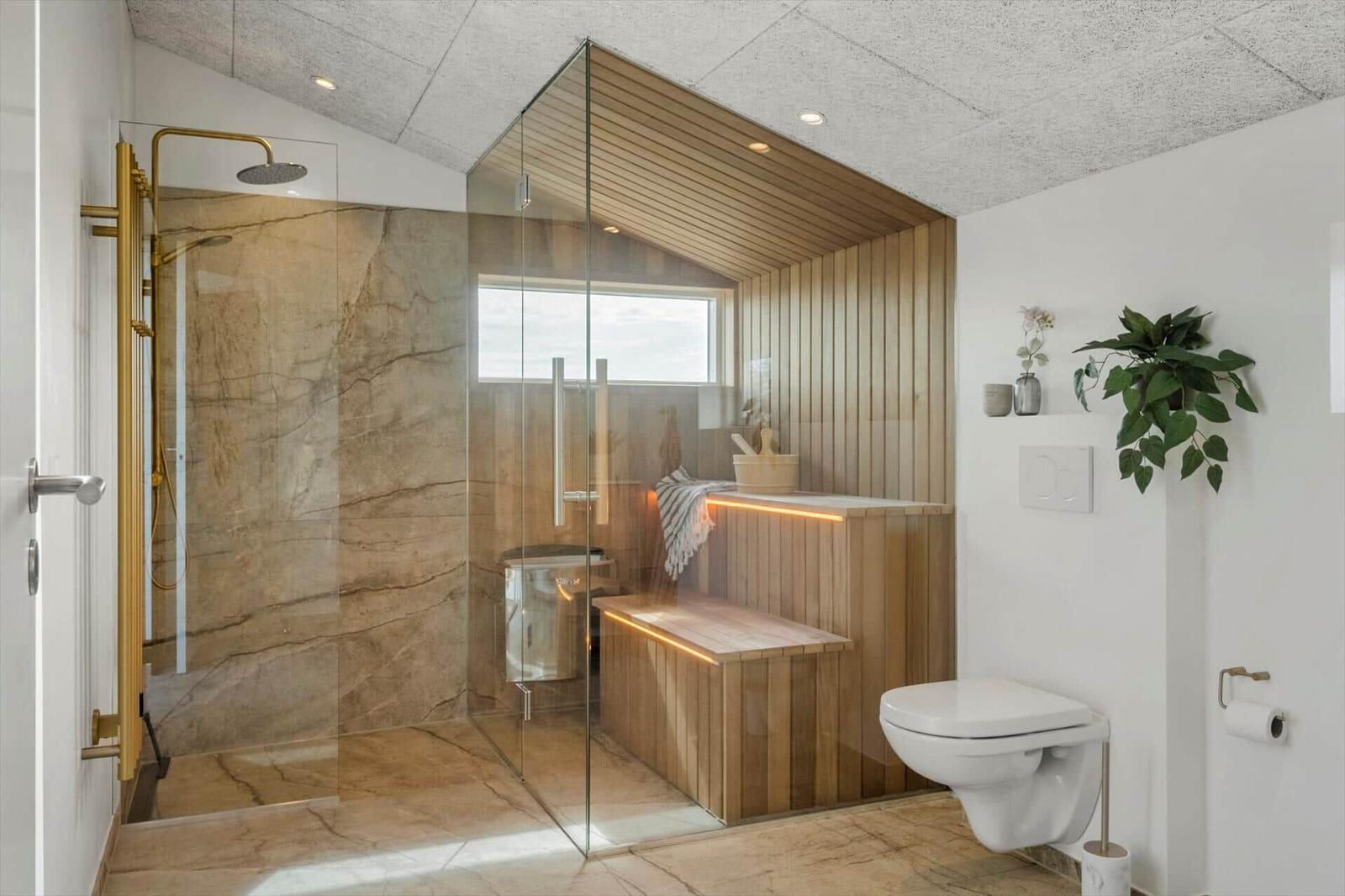 Bad mit Dusche, Sauna und Toilette. Holzwände, Glasabtrennung und marmerne Fliesen.