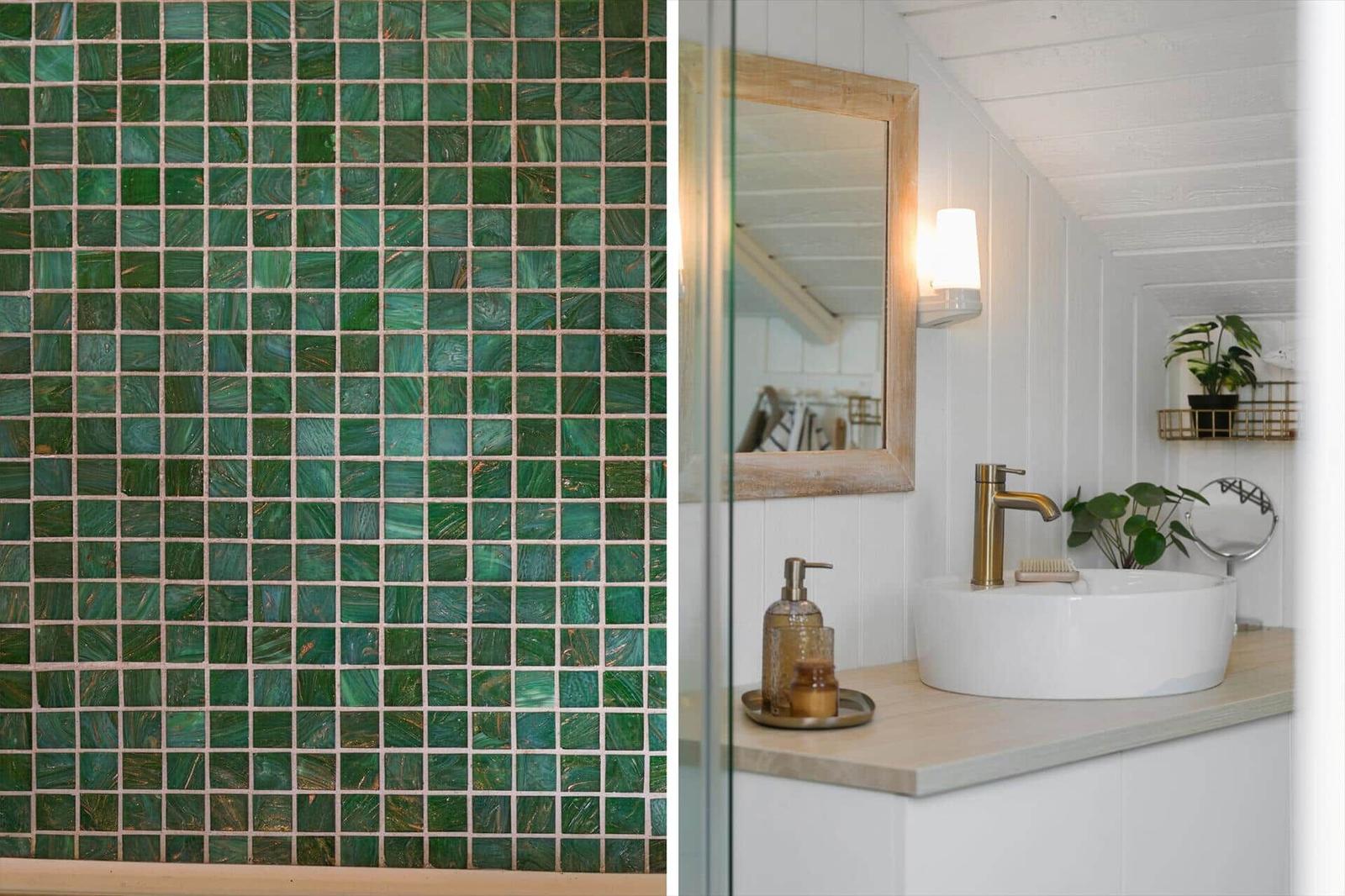 Badezimmer mit grünem Mosaik und weißem Waschbecken auf Holzunterlage.