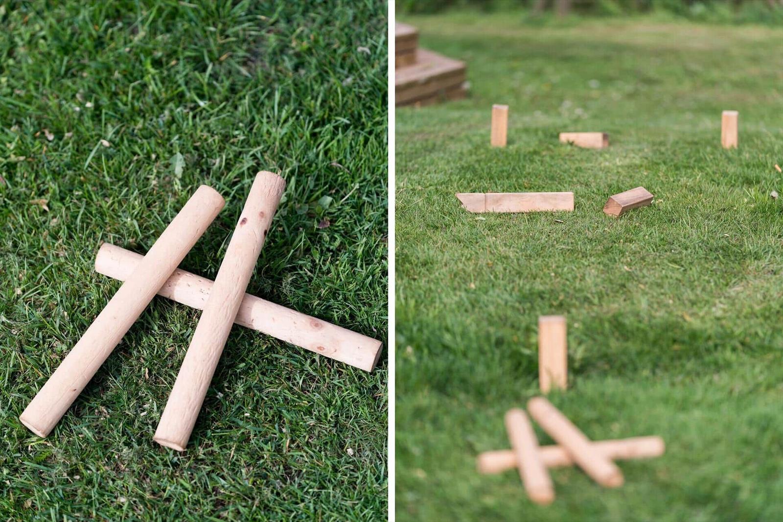 Holzspielzeug auf grünem Rasen. Links: zwei gekreuzte Stäbe. Rechts: mehrere Spielsteine verstreut.