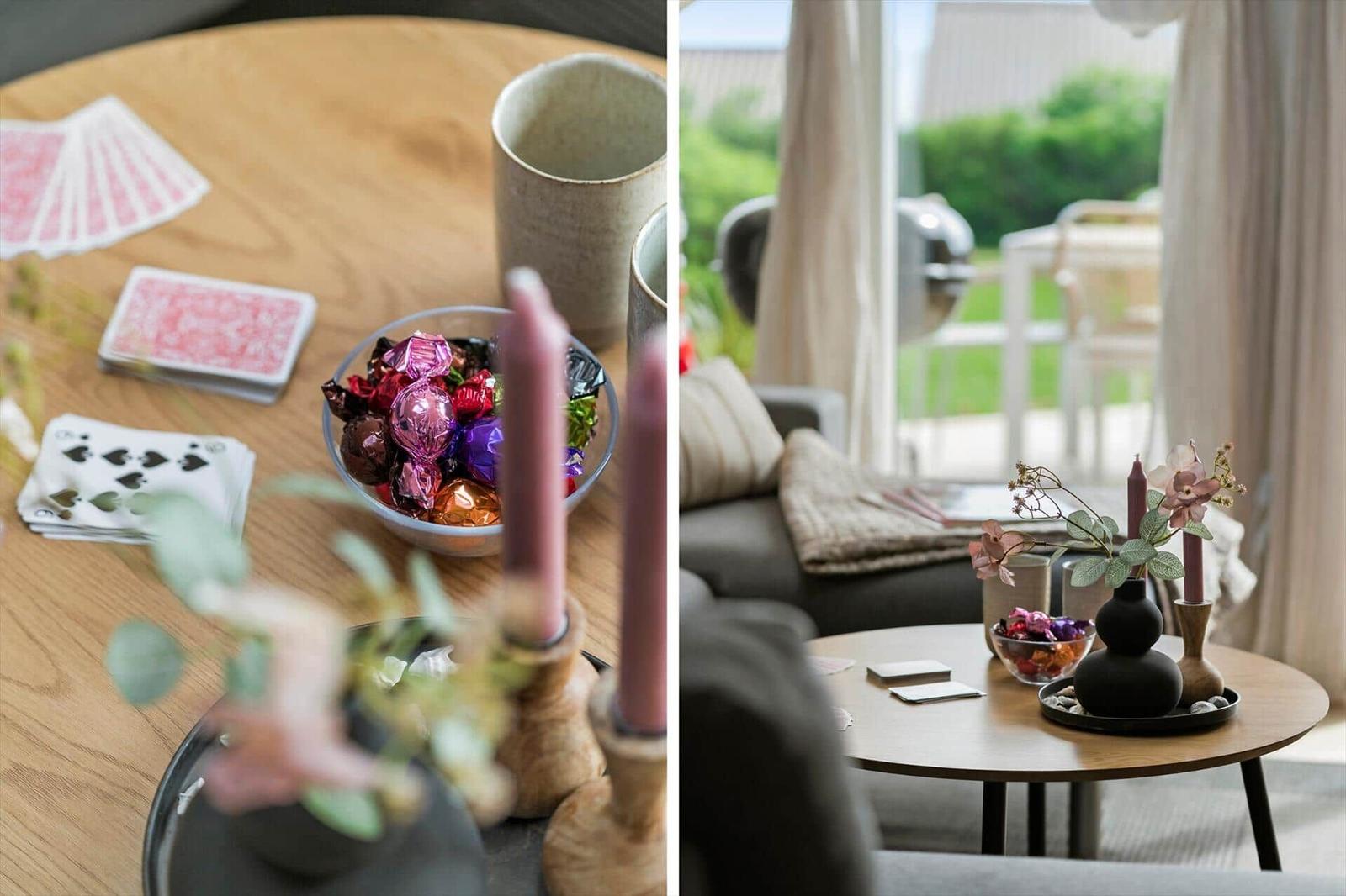 Runde Tisch mit Karten und Süßigkeiten, Blick auf Wohnbereich mit Sofa und Garten.