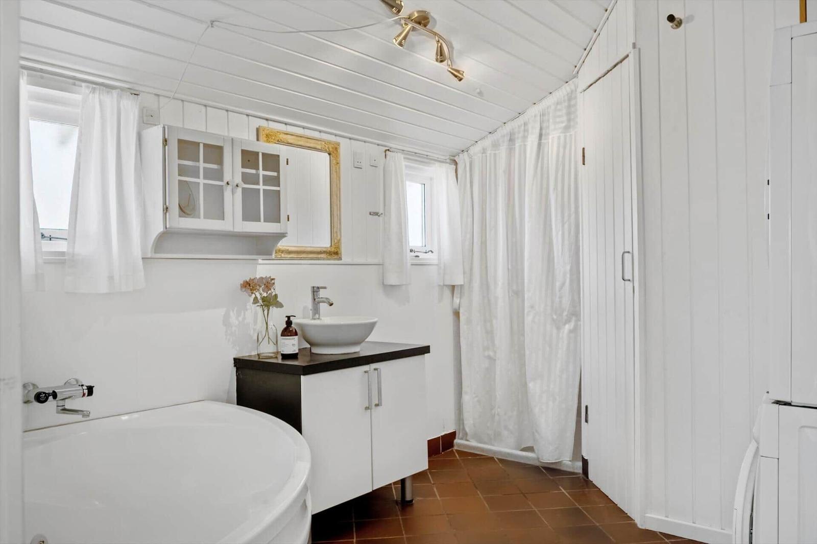 Badezimmer mit Badewanne, Waschtisch und Duschvorhang.