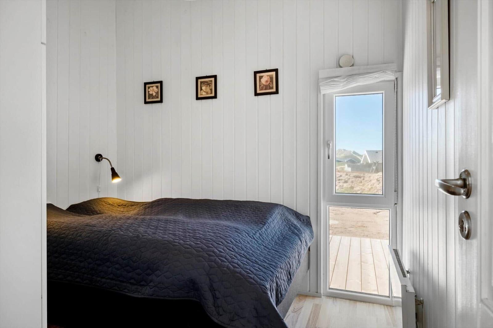 Schlafzimmer mit Bett, Wandbildern und Tür zum Balkon.