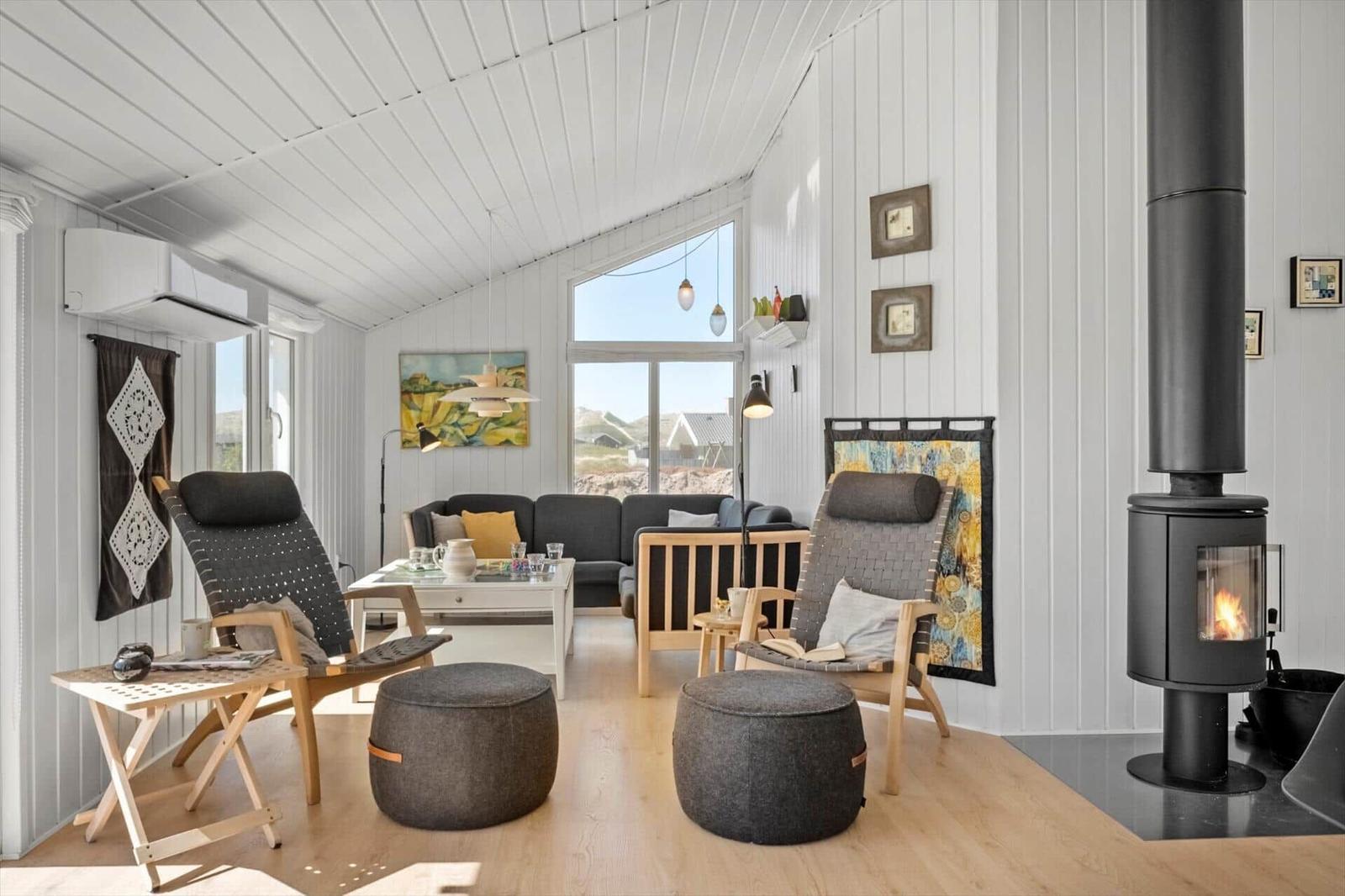 Wohnraum mit Sitzgelegenheiten, Kamin und großem Fenster zur Aussicht.