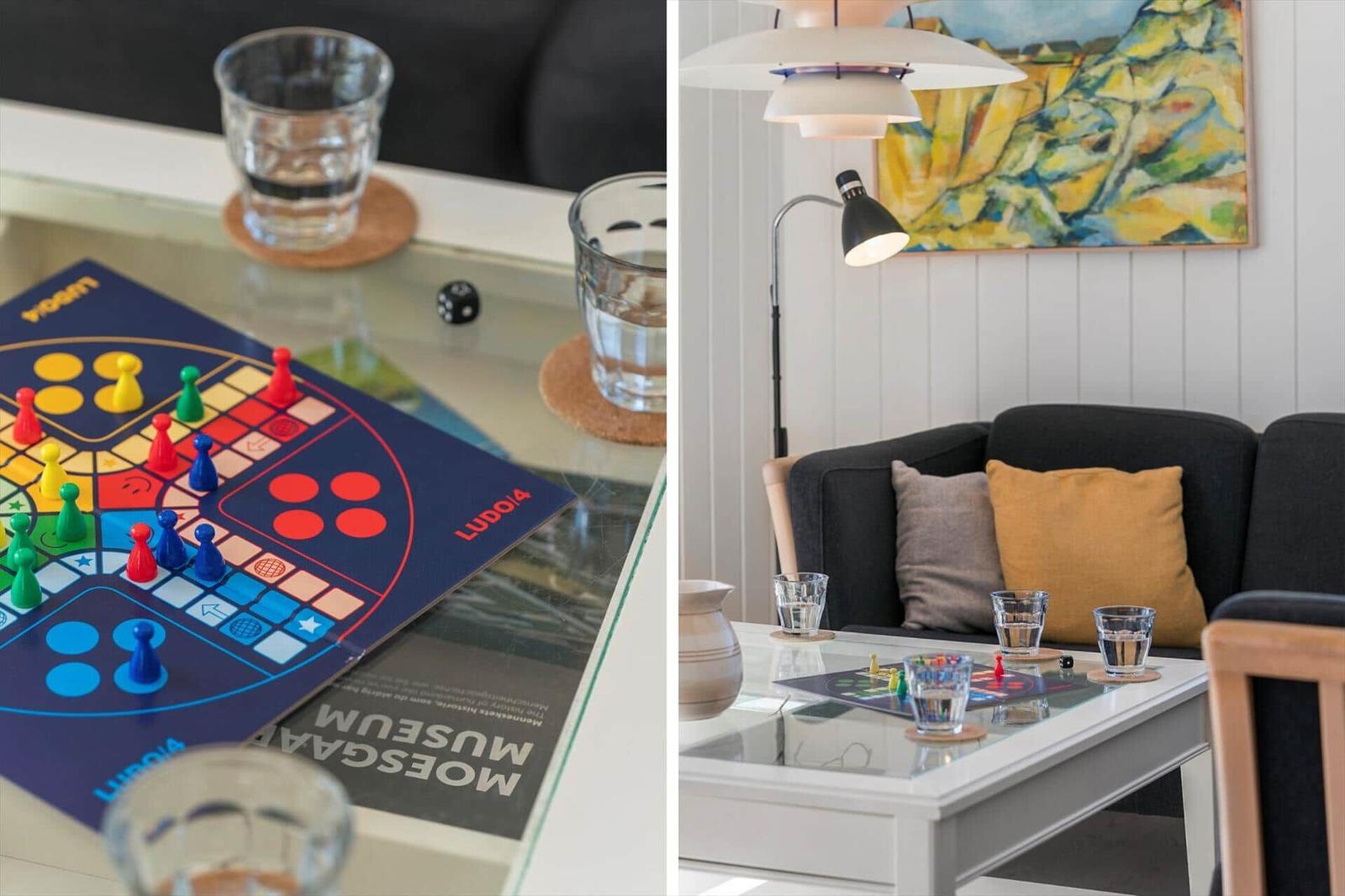 Glas-Tisch mit Ludo-Spiel, Wassergläser und Kissen auf Sofa
