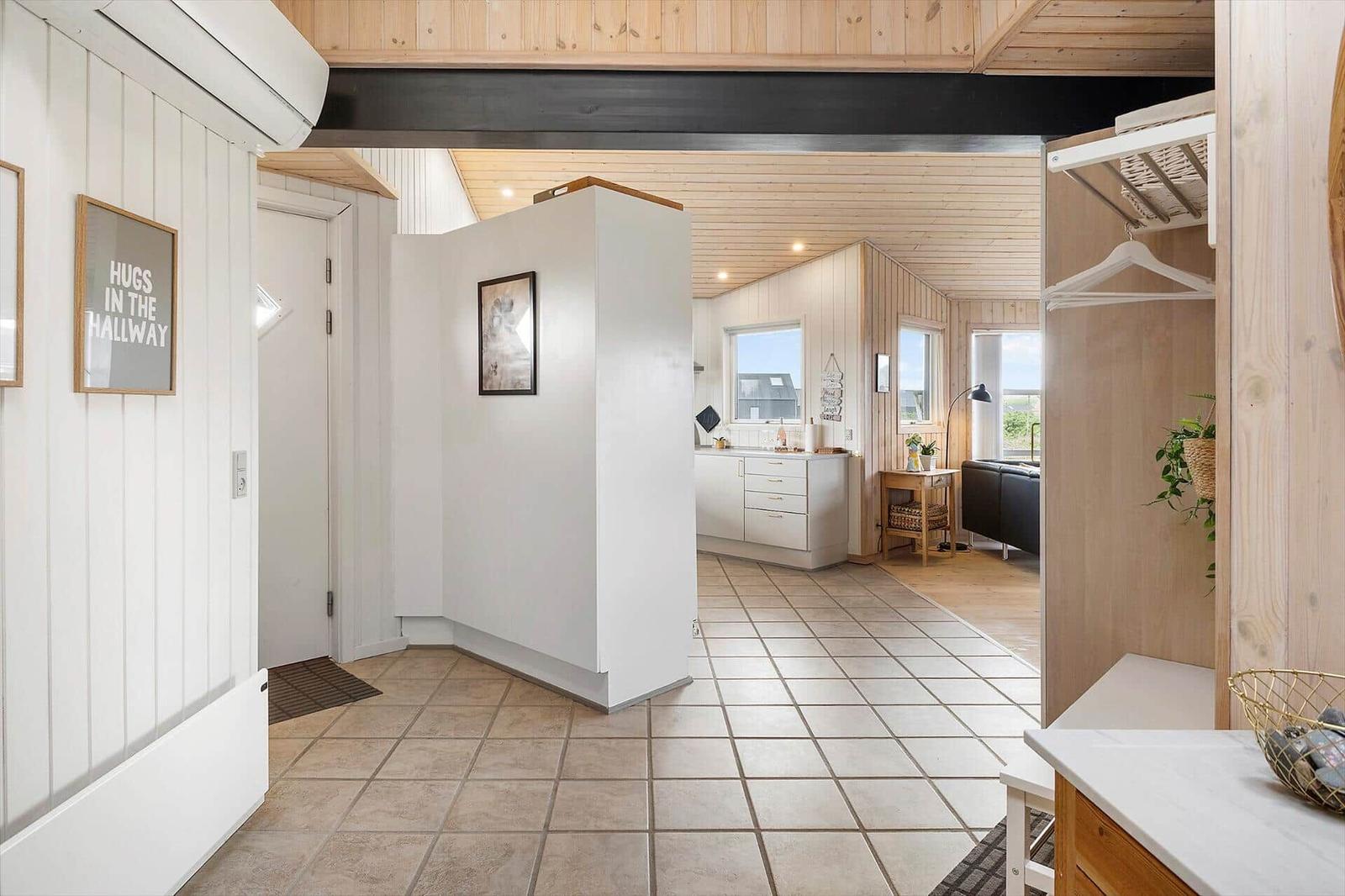 Hallenbereich mit Blick in Küche und Wohnzimmer. Holzdecke und Fliesenboden.