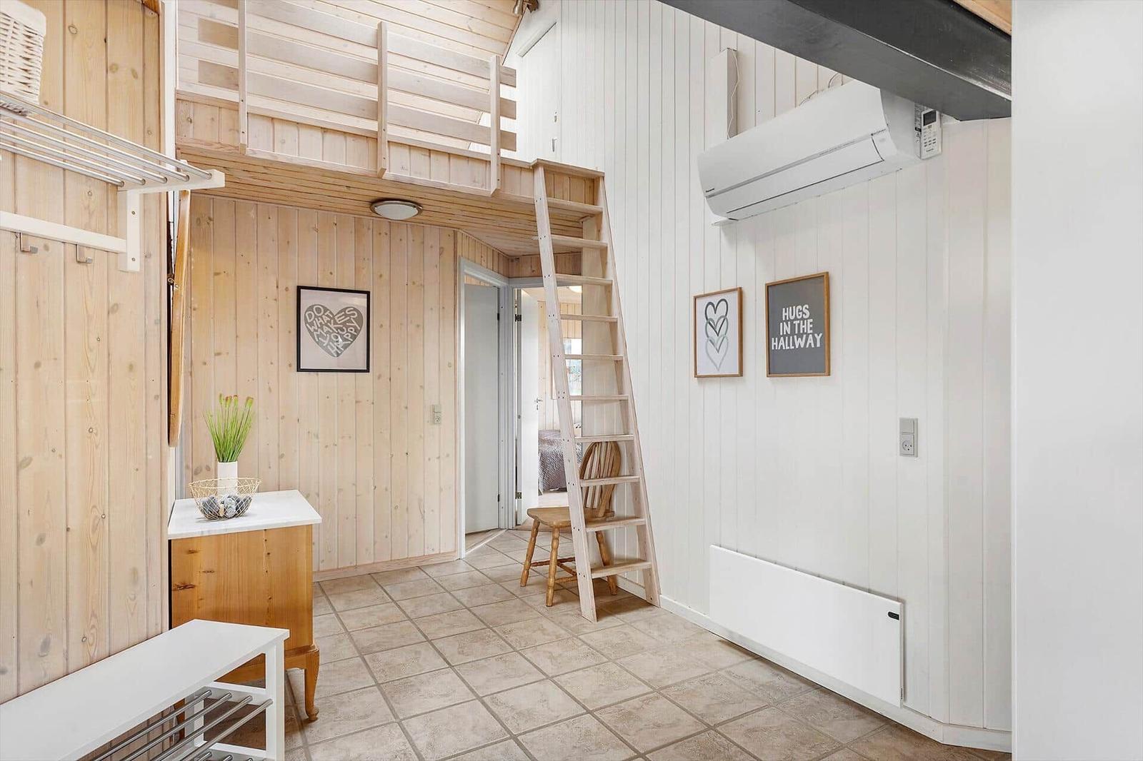 Hallenraum mit Holzwand, Treppe zur oberen Etage und Wandbildern.