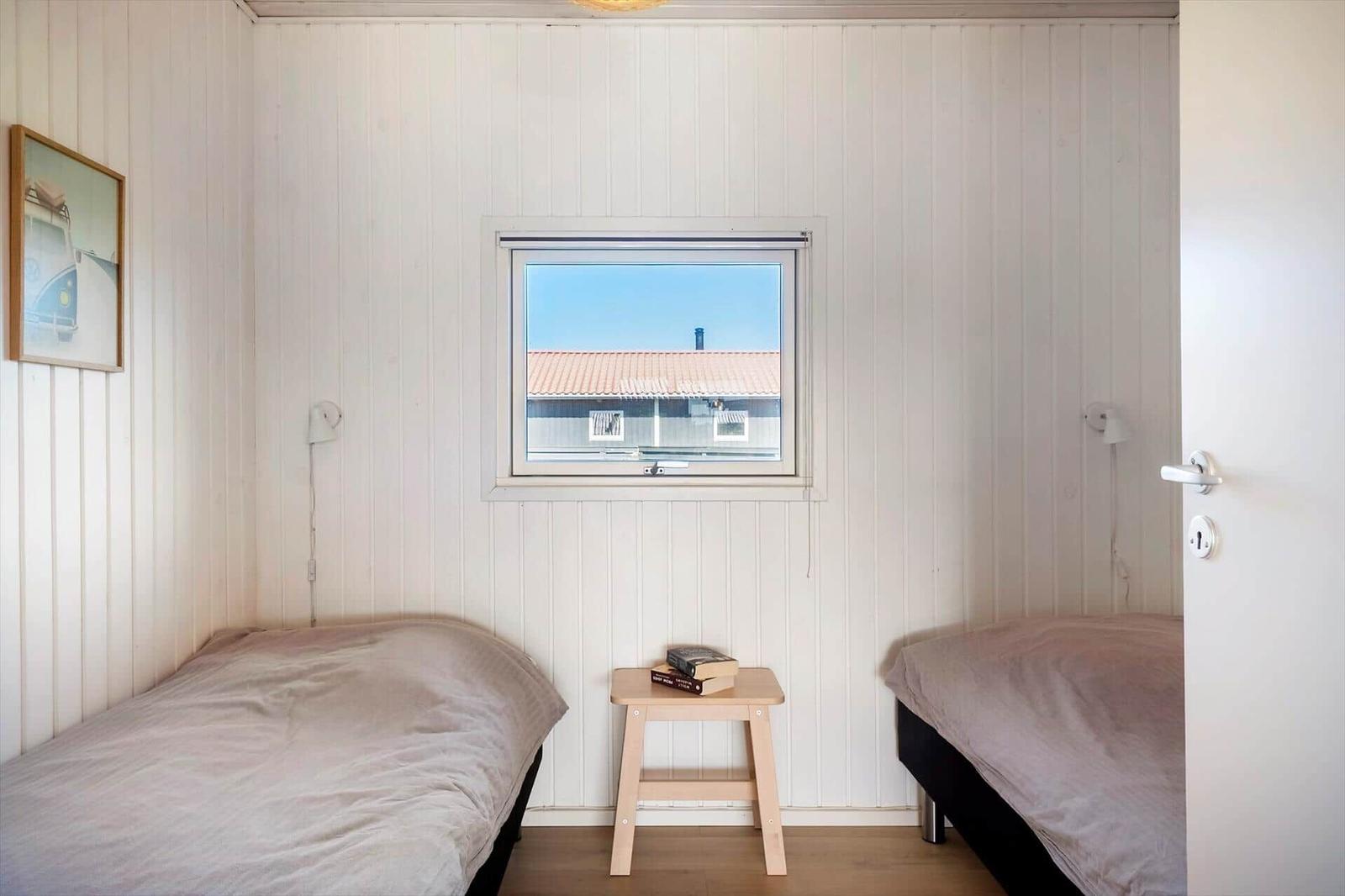Zwei Einzelbetten, ein kleiner Tisch und ein Fenster mit Blick auf ein Haus.