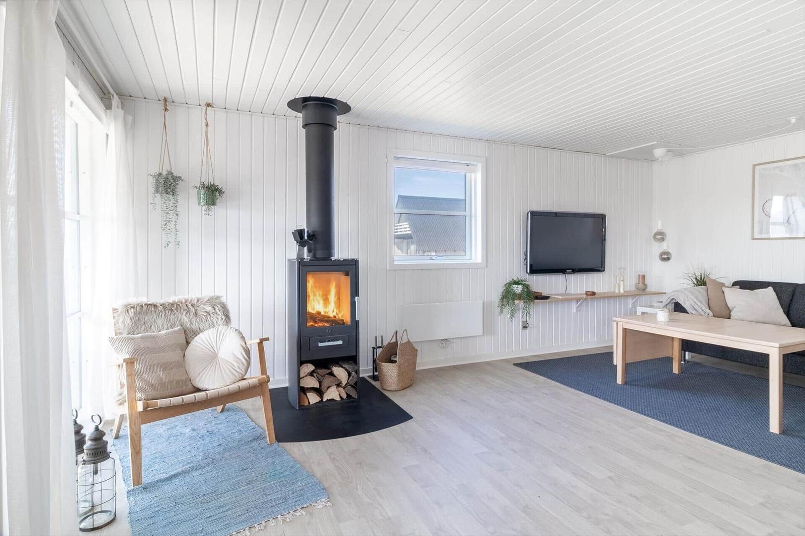 Wohnzimmer mit Kamin, Sofa, Fernseher und Holzboden.