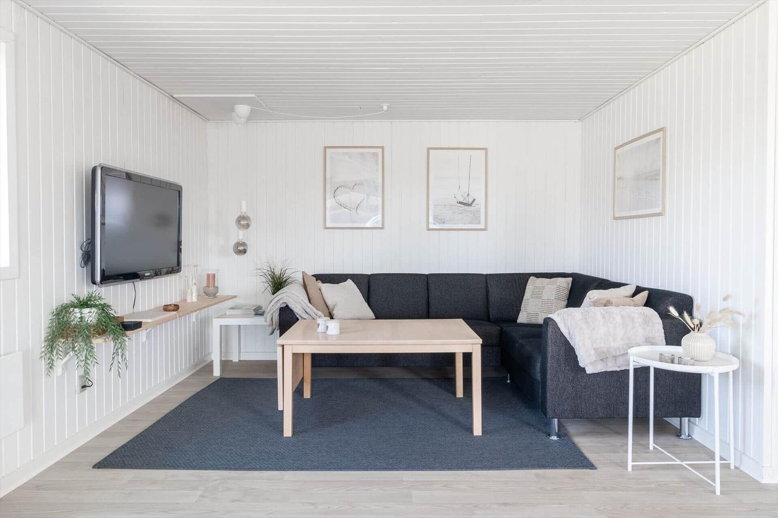 Wohnzimmer mit Sofa, Tisch und Fernseher an der Wand.