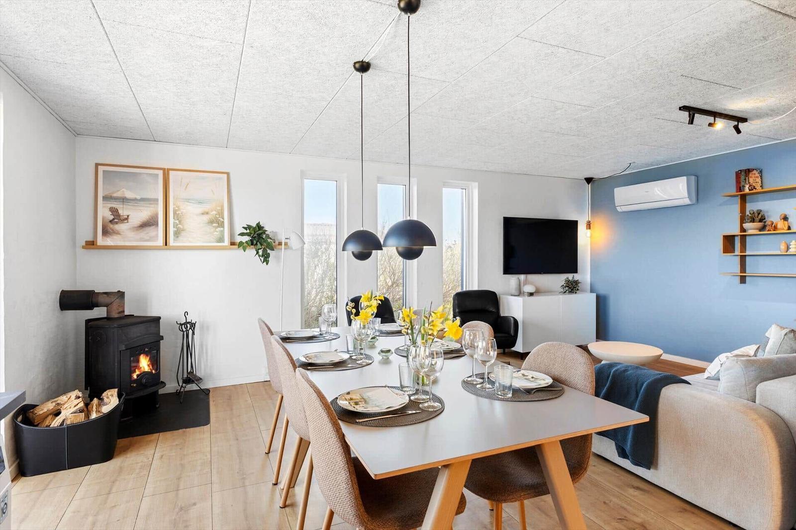 Esszimmer mit Esstisch, Stühlen und Kamin. Wohnbereich mit Sofa und Fernseher.